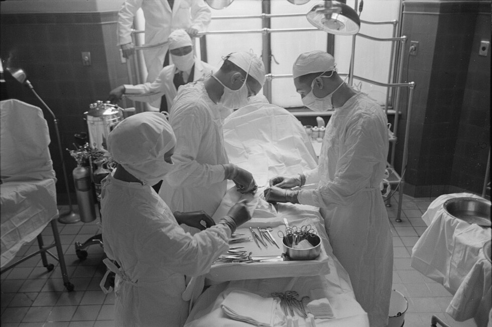 A gowned and masked surgical team at work in the operating theatre of Provident Hospital, Chicago, in 1941, instruments laid out on the tray in front of them